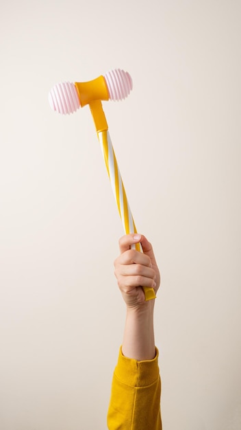 Toy hammer in famele hand against light background