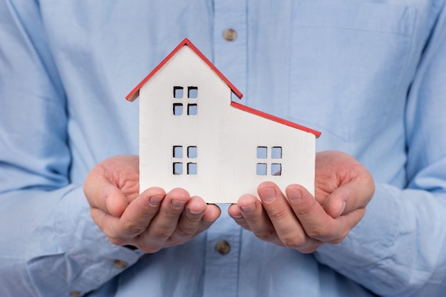 Toy house model in male hands. Buying home, mortgage concept