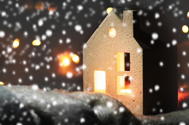 Toy house in winter night snowfall