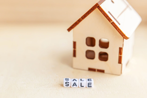 Toy house with SALE word on wooden background