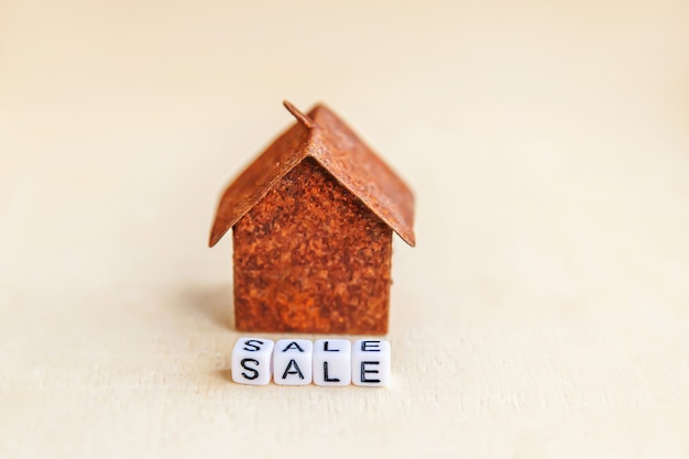 Toy house with SALE word on wooden background