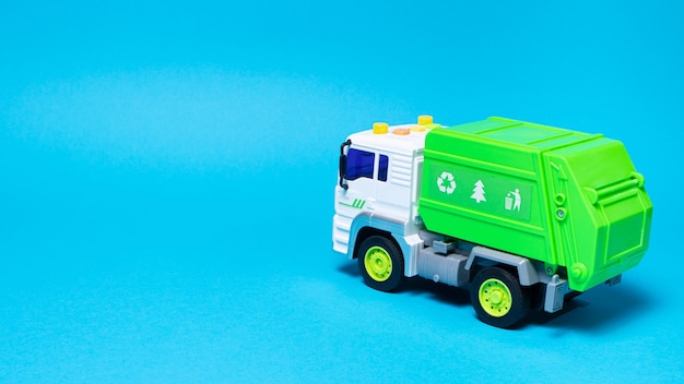 Foto il giocattolo è un camion della spazzatura verde con un corpo bianco su sfondo blu.