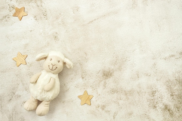 Toy lamb and wooden stars on pastel background. Motherhood concept. Top view, flat lay composition. Copy space for text.