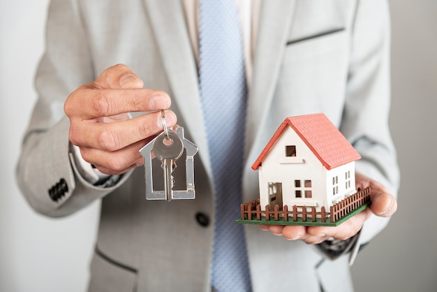 Photo toy model house and keys being held in hands by business person