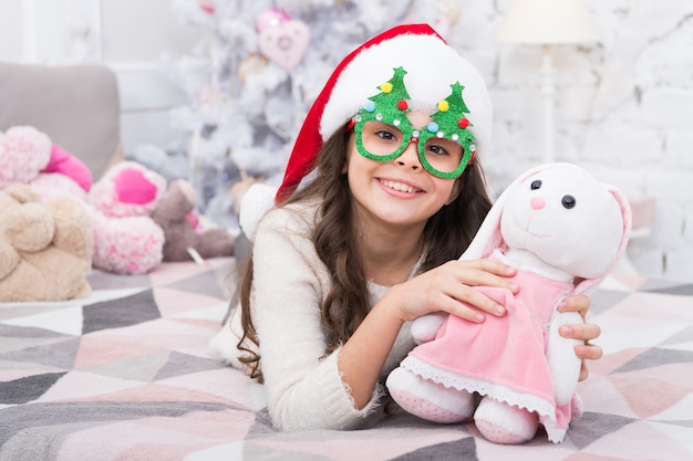 Toy never sleeps. Little girl play with toy bunny. Happy child got toy gift from Santa. Christmas gift or present. Saint Nicholas Day. New Year Eve. Toy and imagination. Game and play.