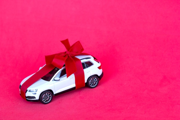 Toy new car gift with red bow on red