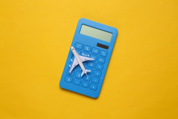 Toy passenger plane and calculator on yellow background