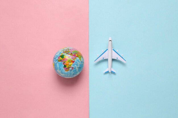 Toy passenger plane and globe on blue pink background voyage travel summer vacation concept top view