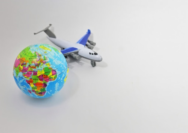 Toy plane and earth globe on white background with copy space Selective focus