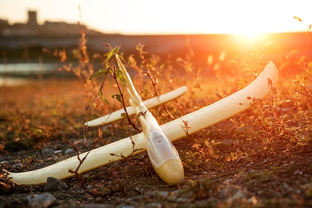 The toy plane lies on the grass at sunset on a grass field in the russian countryside