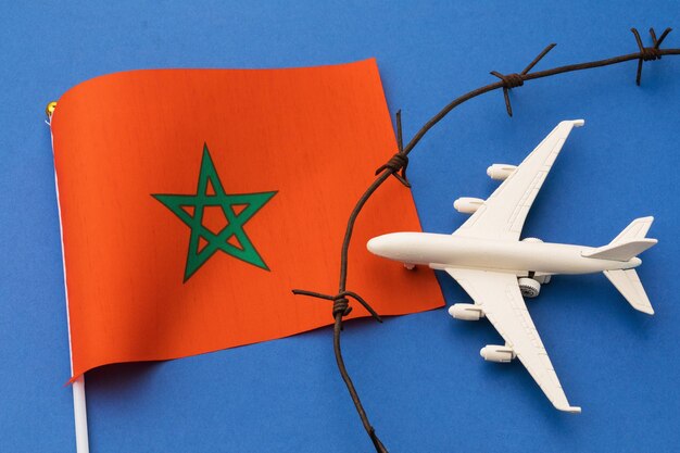 Foto aereo giocattolo, bandiera marocchina e filo spinato su sfondo colorato, concetto di violazione del confine aereo del marocco