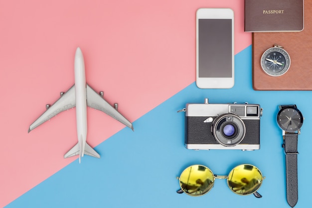 青とピンクのパステルの背景に旅行オブジェクトとおもちゃの飛行機