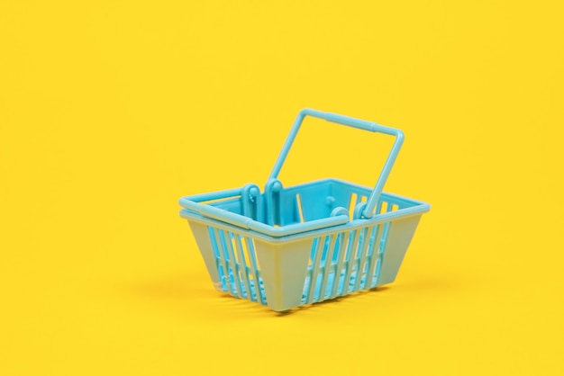 Toy plastic shopping basket on yellow