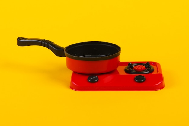 Toy plastic stove with pan on a yellow. Kid's Kitchen