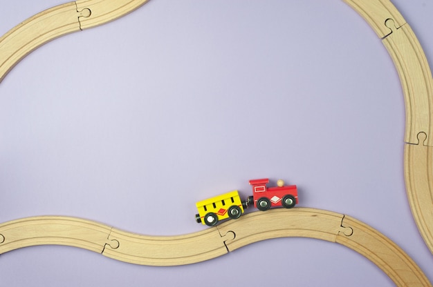 Toy railway and a small train on a purple background. Flat lay, Top view. Travel concept