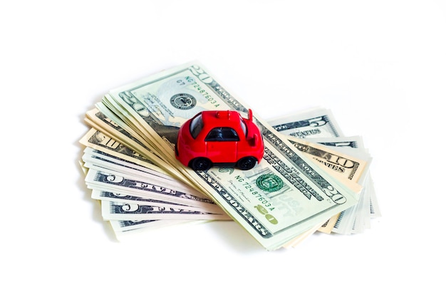 Foto giochi l'automobile rossa sulla pila di banconote in dollari dei soldi. dollari americani. comprare auto a credito. risparmiare per il veicolo.