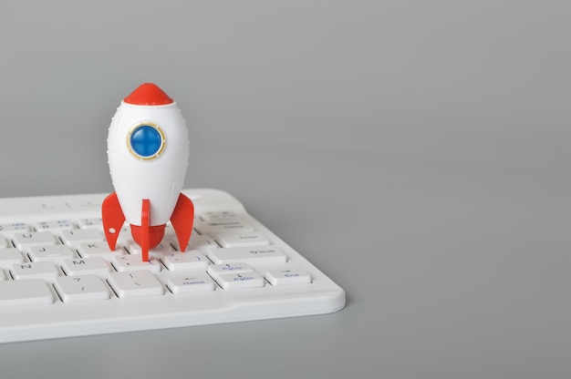 Toy rocket and laptop keyboard isolated on a grey backgroundThe symbol for success is Startup business education and knowledge