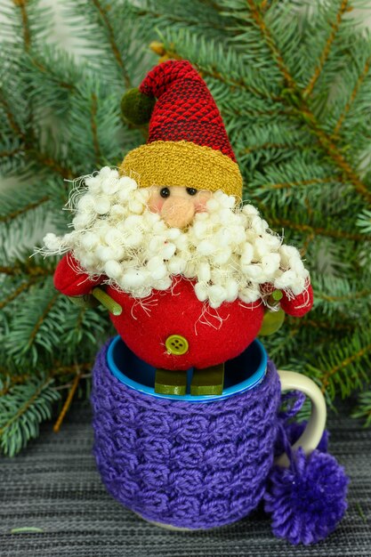 Toy Santa Claus on skis on the background of fir branches and mugs.