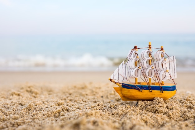 Toy ship on the sand by the sea. Summer vacation concept