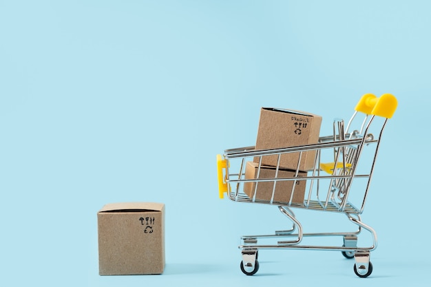 Photo toy shopping cart with boxes on blue background