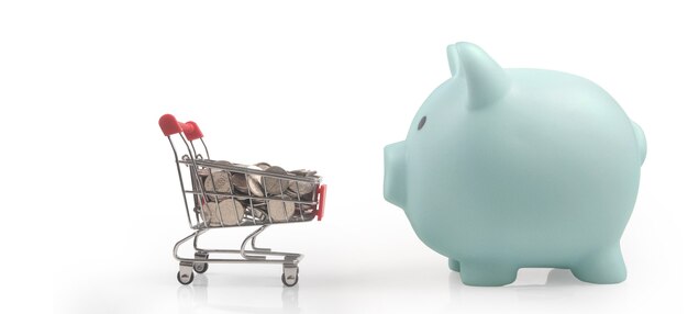 Toy shopping cart with boxes shopping and Piggy bank . Consumer society trend