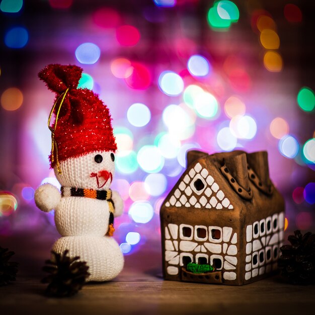 Foto pupazzo di neve giocattolo e casa di pan di zenzero al tavolo di natale .foto con spazio di copia.