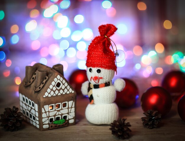 Pupazzo di neve giocattolo e casa di pan di zenzero al tavolo di natale