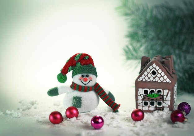 Игрушечный снеговик и пряничный домик на светлом фоне