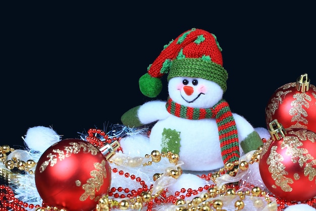 Toy snowman with a red festive balls and decorations in the black background