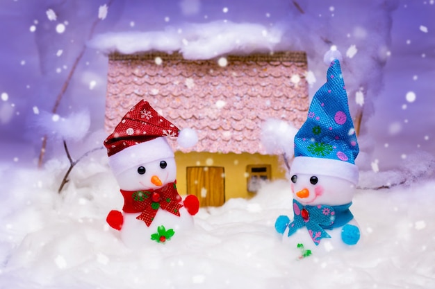 Toy snowmen with house during snowfall