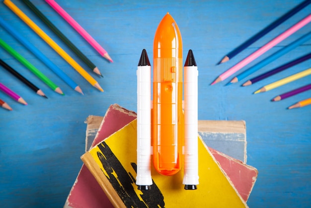 Photo toy space shuttle and colored pencils on blue background