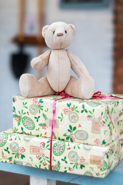 Toy teddy bear and christmas gifts on porch of  house on a winter day