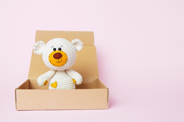 Toy teddy bear in a craft box isolated on a pink background. Baby background. Copy space, top view