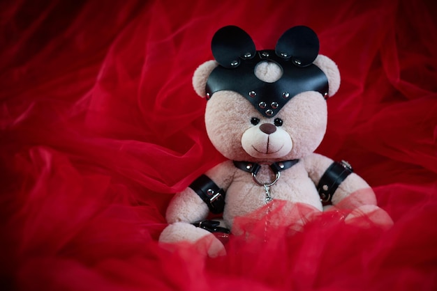 A toy teddy bear dressed in leather belts and a mask an accessory for BDSM games