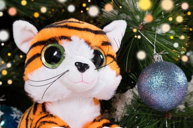 Foto tigre giocattolo sullo sfondo dell'albero di natale.