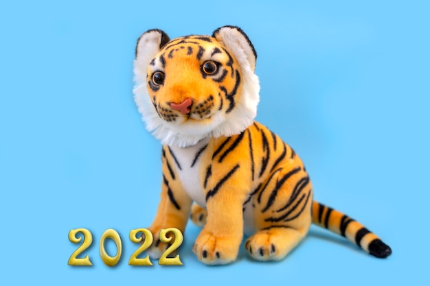 Toy tiger on the blue background Symbol of the year 2022 Year of the tiger golden inscription 2022