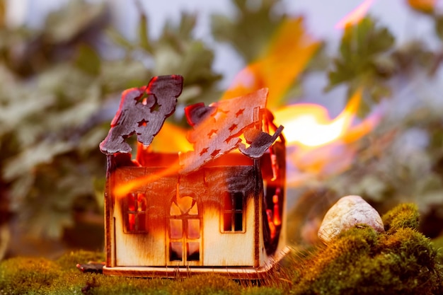 おもちゃの木造住宅が自然の中で燃えています 火の概念 火の安全