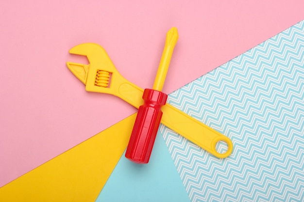 Photo toy wrench and screwdriver on a colored pastel background. top view. minimalism