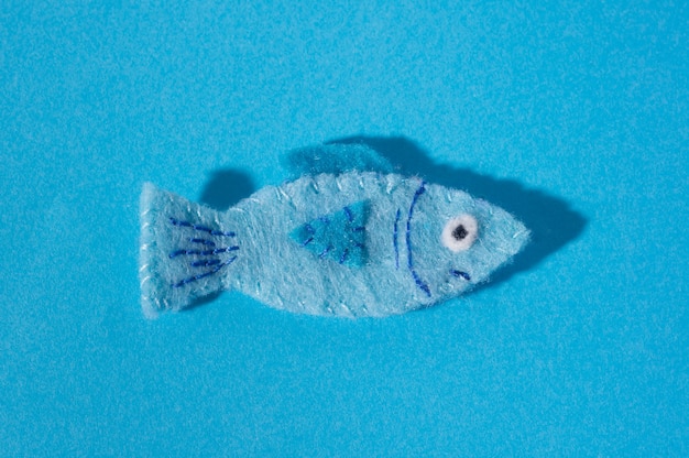 写真 青い背景にフェルトで作られた魚の手作りの形のおもちゃ。手縫い
