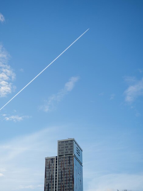 Photo a trace from the flight of an airplane against the backdrop of a tall building