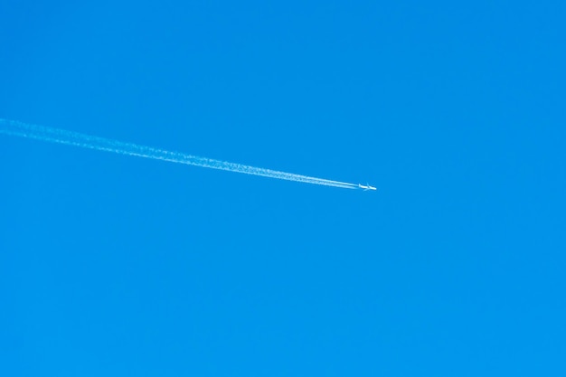 The trace of the plane in the sky white traces of a jet stream
from the combustion of aviation fuel a passing plane draws white
lines on a blue sky without clouds