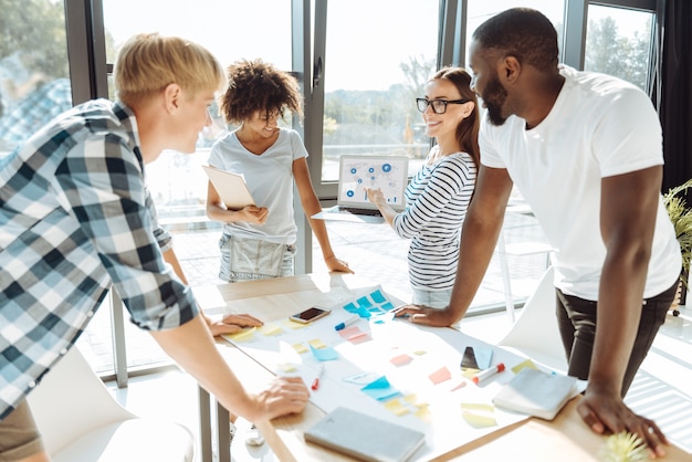 Trace the tendency. Cheerful enthusiastic young people discussing their business project and working together while expressing their ideas