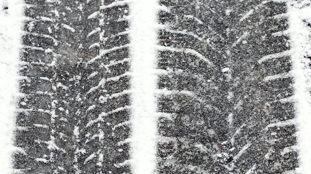 Photo traces of car tires in the snow, slippery road