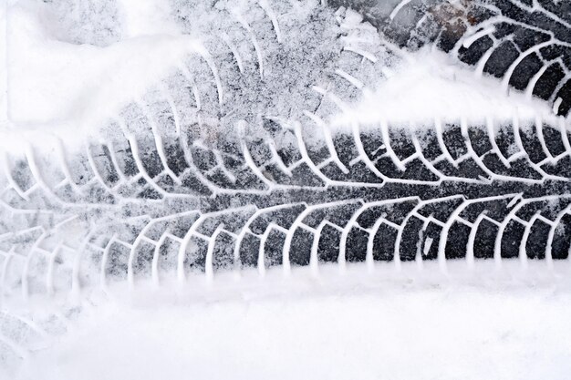 Traces of the car on a white fresh snow on the asphalt background