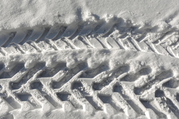 Photo traces of a wheeled tractor in the snow closeup winter snow patterns