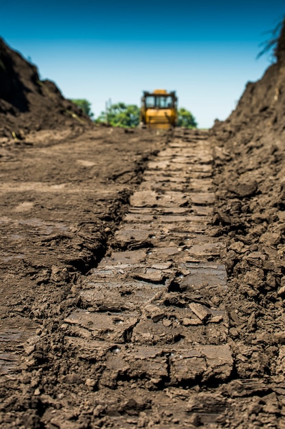 Traccia il bulldozer giallo con il trattore cingolato in piedi in un campo