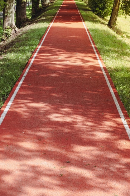 Track and Field Park. Healthy sport. Jogging track at beautiful park. A red jogging track in the par