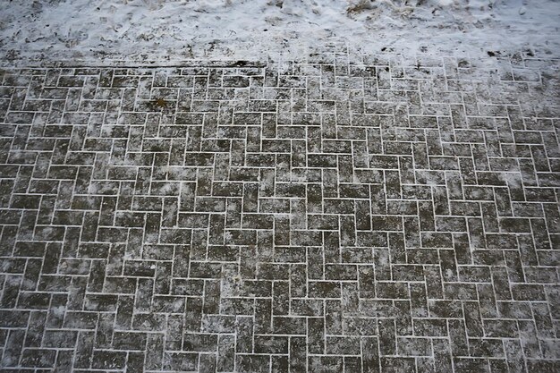 アスファルトの雪、氷、雪の上の靴からの人々のトラック、除雪の天気を追跡します