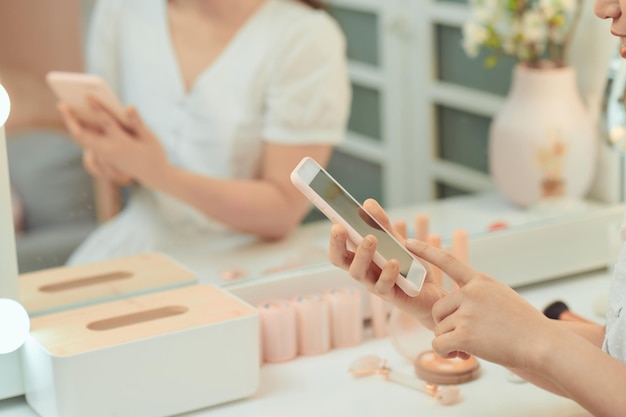 La ragazza di tractive si fa selfie con un telefono allo specchio con lampade nello studio di bellezza