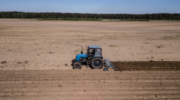 Tractor - aerial view of a tractor at work - cultivating a field in spring with blue sky - agricultural machinery